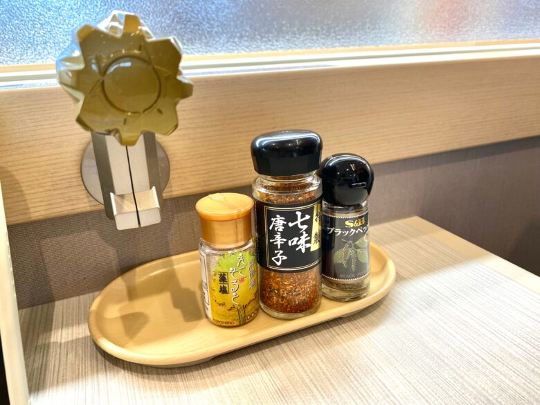 はま寿司伏見新堀川店のテーブルに設置されている藻塩、七味唐辛子、ブラックペッパー